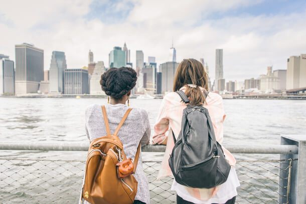 Two women looking at the Manhattan skyline across the river. 