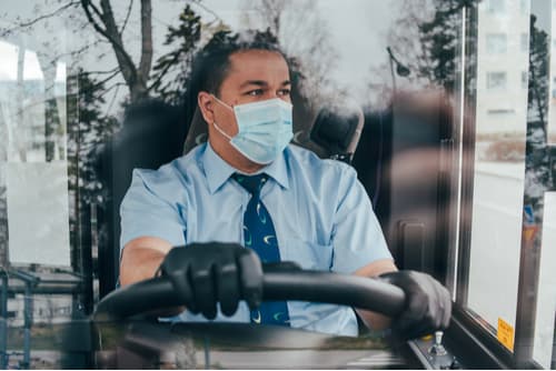 a charter bus driver wearing a mask and gloves