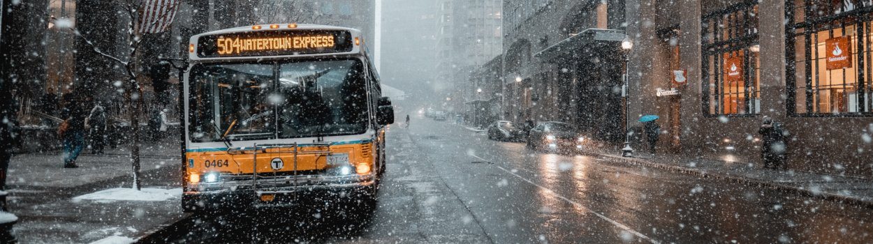 A bus driving on a street while it is snowing. 